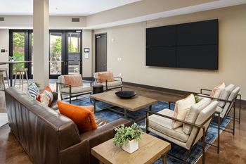 A living room with a brown couch, a coffee table, and a flat screen TV mounted on the wall.